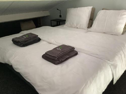 two suitcases sitting on top of a white bed at Gastenverblijf Dalem met hottub en landelijk in Hapert