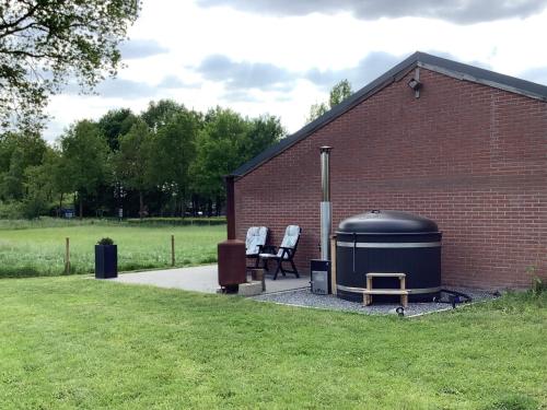 a brick building with two chairs and a water tank at Gastenverblijf Dalem met hottub en landelijk in Hapert