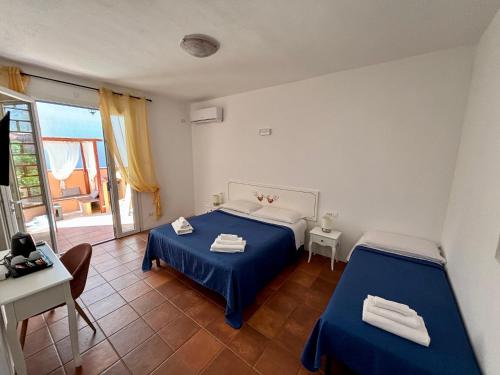 a bedroom with two beds and a table and a window at B&B De Janas in La Caletta