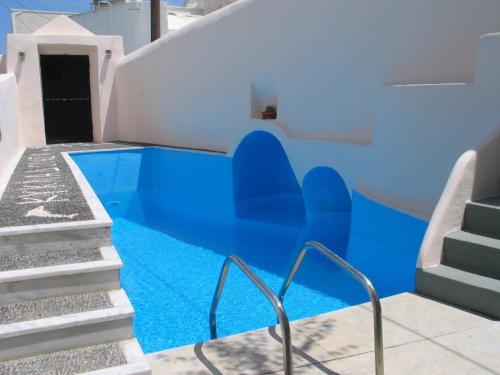 a swimming pool with blue water next to stairs at Kykladonisia Traditional Settlement in Fira