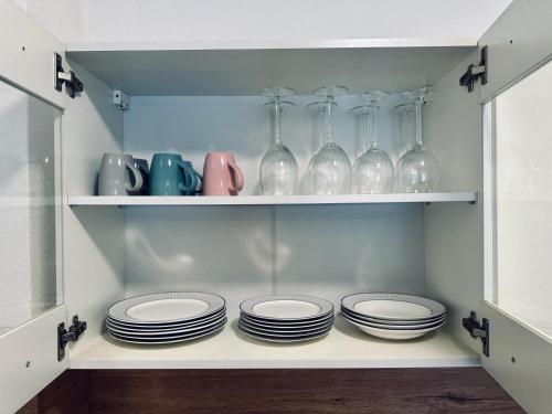 a shelf with plates and glass vases on it at FeWo Am Hang mit Balkon im Grünen in Bad Bentheim
