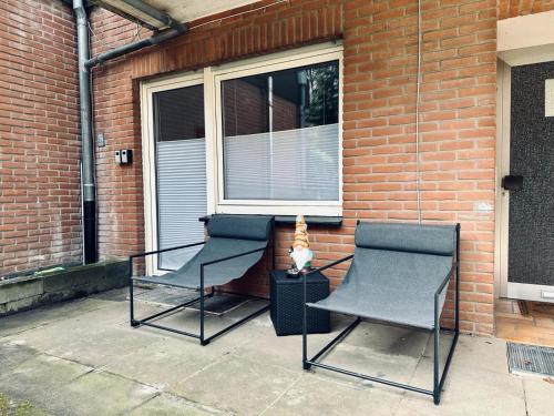 two chairs sitting in front of a brick house at FeWo Am Hang mit Balkon im Grünen in Bad Bentheim