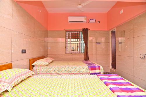 2 camas en una habitación con paredes de color naranja en Selva Homestay en Kanchipuram