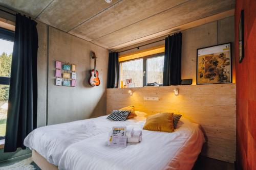 a bedroom with a bed in a room with a guitar at Daft Boutique Hotel & Glamping in Malmedy