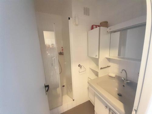 une salle de bain blanche avec un lavabo et une douche dans l'établissement Charmant T2 entre Plage et Commerces avec TV, Cuisine équipée, Animaux admis à Saint-Hilaire-de-Riez - FR-1-324A-27, à Saint-Hilaire-de-Riez