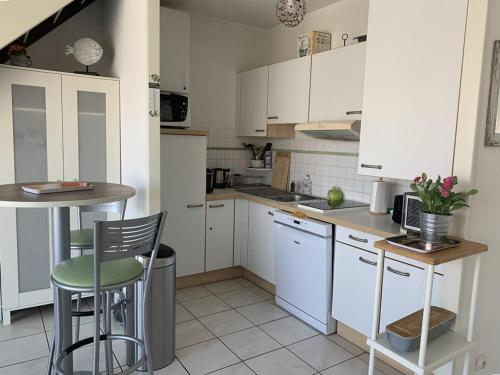 une cuisine avec des armoires blanches et une table et des chaises dans l'établissement Duplex climatisé 4 pers, balcon, parking privé, proche plages et commerces - FR-1-335-168, à Hyères