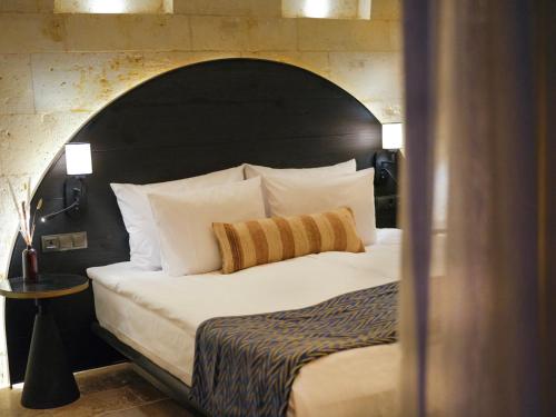 a bedroom with a large bed with a black headboard at Very Peri Cappadocia - The Lifestyle Luxury Design Hotel in Uchisar