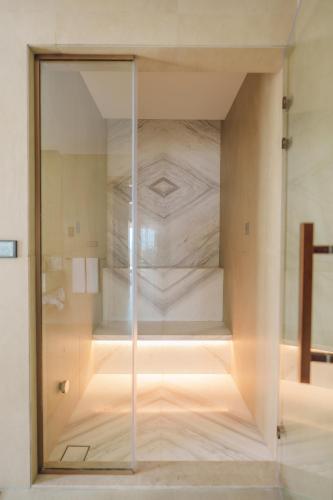 a glass walled shower in a bathroom with a shower at Naama Beach Villas & Spa in Al Aqah