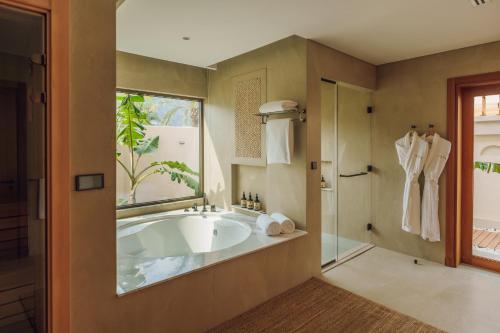 a bathroom with a large tub and a window at Naama Beach Villas & Spa in Al Aqah