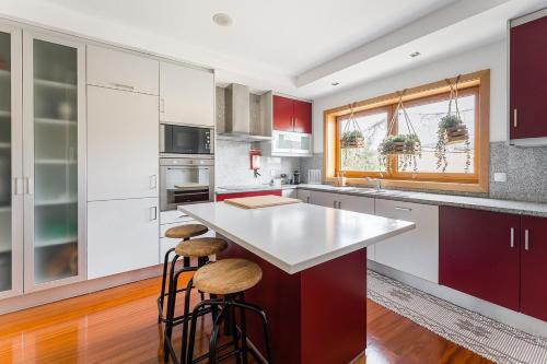 a kitchen with red and white cabinets and stools at GuestReady - Sophistication and refinement in Vila Nova de Gaia