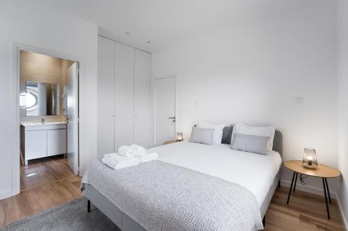 a white bedroom with a large bed and a table at GuestReady - Casas de Fralães in Barcelos