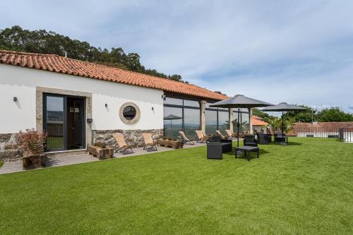 a lawn with chairs and umbrellas on a house at GuestReady - Casas de Fralães in Barcelos
