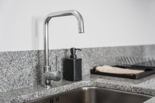 a kitchen sink with a faucet on a counter at GuestReady - Casas de Fralães in Barcelos