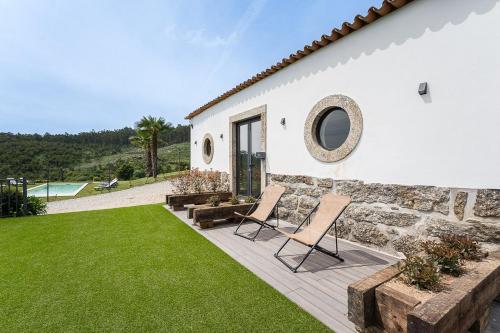 une maison blanche avec deux chaises et une pelouse dans l'établissement Scenic countryside getaway, à Barcelos