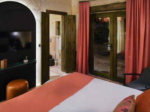 a bedroom with a bed with red curtains and a television at Very Peri Cappadocia - The Lifestyle Luxury Design Hotel in Uchisar