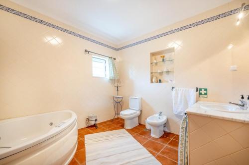 a bathroom with a tub and a toilet and a sink at Refreshing poolside escape in Ponte de Sor in Ponte de Sor