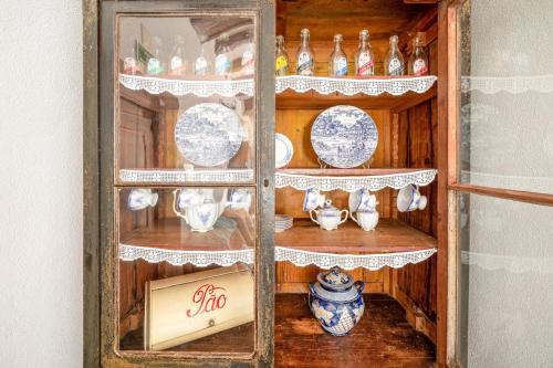 a wooden cabinet filled with dishes and vases at Refreshing poolside escape in Ponte de Sor in Ponte de Sor