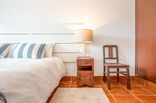 a bedroom with a bed and a chair and a lamp at Refreshing poolside escape in Ponte de Sor in Ponte de Sor