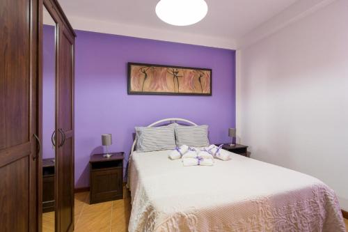 a purple bedroom with a white bed with two pillows at Paraíso dos viajantes do tempo em Góis 