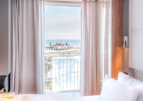 a bedroom with a large window with a view of the ocean at Das Ahlbeck Hotel & SPA in Ahlbeck