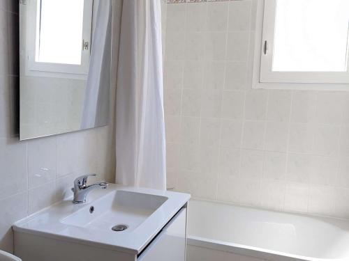 La salle de bains blanche est pourvue d'un lavabo et d'une baignoire. dans l'établissement Maison Duplex avec Piscine et Proche Plage, Parking Inclus - FR-1-387-197, à Marseillan