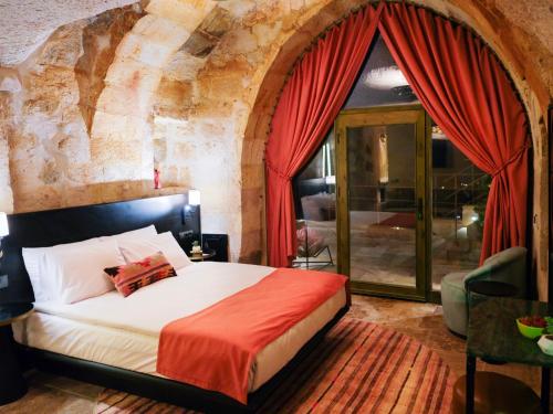 een slaapkamer met een groot bed met rode gordijnen bij Very Peri Cappadocia in Uchisar