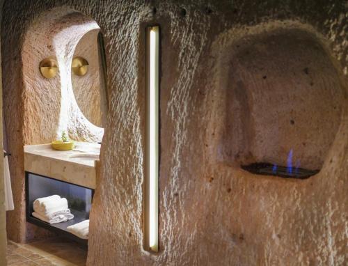 a bathroom with a stone wall with a mirror at Very Peri Cappadocia - The Lifestyle Luxury Design Hotel in Uchisar