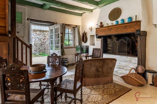 una sala da pranzo con tavolo e camino di La maison du Cocher a Pleyber-Christ