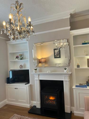 a living room with a fireplace and a chandelier at The Lily Pad - Boutique Townhouse, a short walk to Town Center and Racecourse in Cheltenham