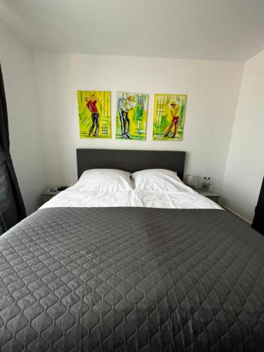 a bedroom with a bed with three paintings on the wall at Aggerschlösschen in Wahlscheid