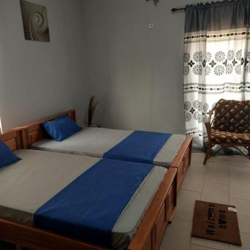 Estepona Playa Hostel في آكرا: غرفة نوم بسريرين وكرسي ونافذة