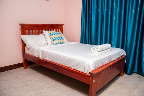 Bett in einem Zimmer mit einem blauen Vorhang in der Unterkunft 2 BEDROOM SPACIOUS APARTMENT-KISASI in Kampala