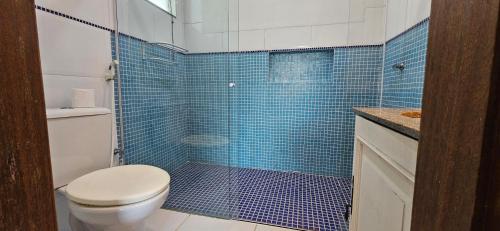a blue tiled bathroom with a toilet and a shower at Kite Nômade in Arraial do Cabo