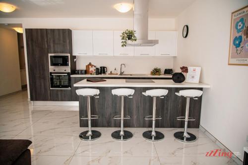 a kitchen with white cabinets and bar stools at Mensija Valley Residences in St Julian's