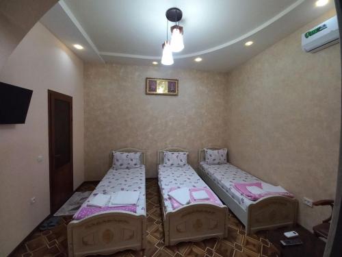 a room with two beds and a tv in it at Yusuf Gold House in Samarkand