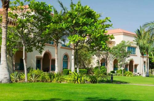 una casa con césped verde y palmeras en Al Raha Beach Hotel - Superior Room SGL - UAE en Abu Dabi