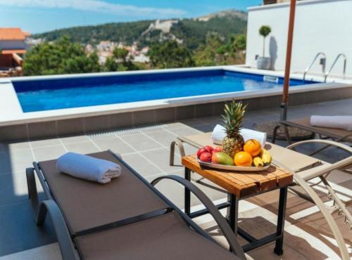 a bowl of fruit on a table next to a pool at Apartments Trogrlić in Hvar