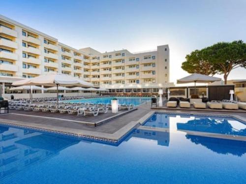 a hotel with a swimming pool with chairs and umbrellas at Albufeira Sol Villas III by Stay ici in Albufeira