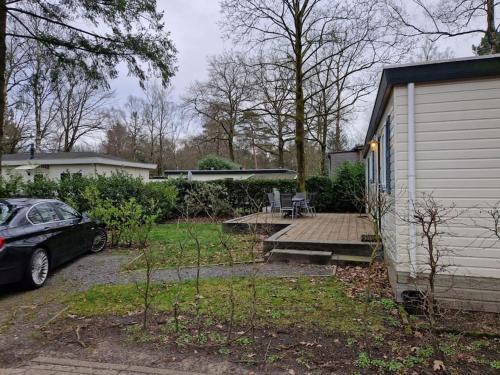 a house with a car parked next to a driveway at 6 persoons chalet op de Veluwe bij binnen en buiten zwembad in Arnhem