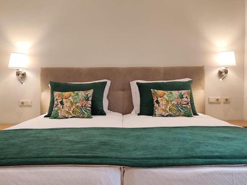 a large bed with green and white sheets and pillows at Albufeira Sol Villas III by Stay ici in Albufeira