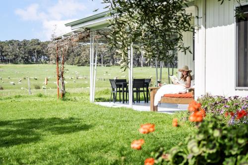 a woman sitting on a chair on the porch of a house at Farm View Cottage in Margaret River Town