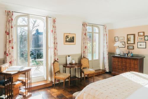 a bedroom with a bed and a desk and two windows at Les Tilleuls Etretat in Étretat