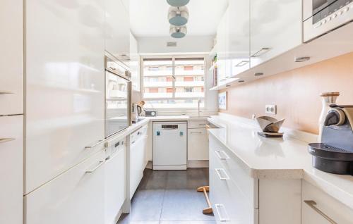 une cuisine avec des armoires blanches et des appareils électroménagers blancs dans l'établissement Awesome Apartment In Paris With Wifi, à Paris