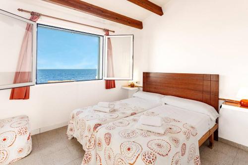 a bedroom with a bed and a large window at Villa Victor - Primera linea mar, vista a puesta de sol in Cala en Blanes