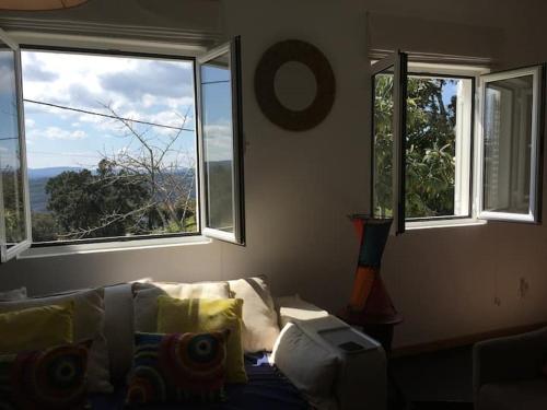 uma sala de estar com um sofá e três janelas em GuestReady - Nature's Haven Retreat em Pedrógão Pequeno