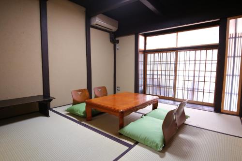 a room with a wooden table and chairs and windows at And Machiya Inn in Kyoto