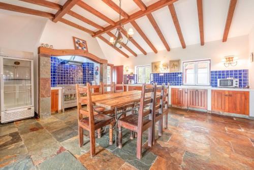 uma cozinha com uma mesa de madeira e cadeiras em Stunning mansion in São Cristóvão em Montemor-o-Novo