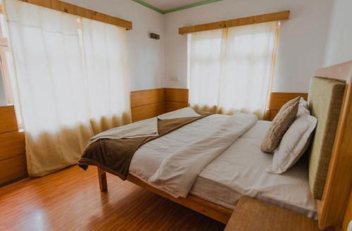 a large bed in a room with two windows at Hotel Lumbini in Leh
