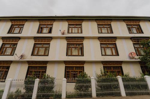 a white building with windows and a white fence at Hotel Lumbini in Leh
