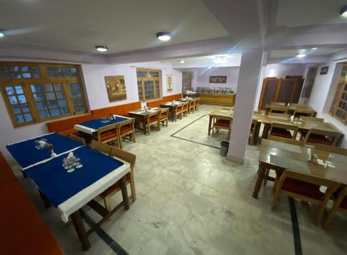 a dining room with tables and chairs in a restaurant at Hotel Lumbini in Leh